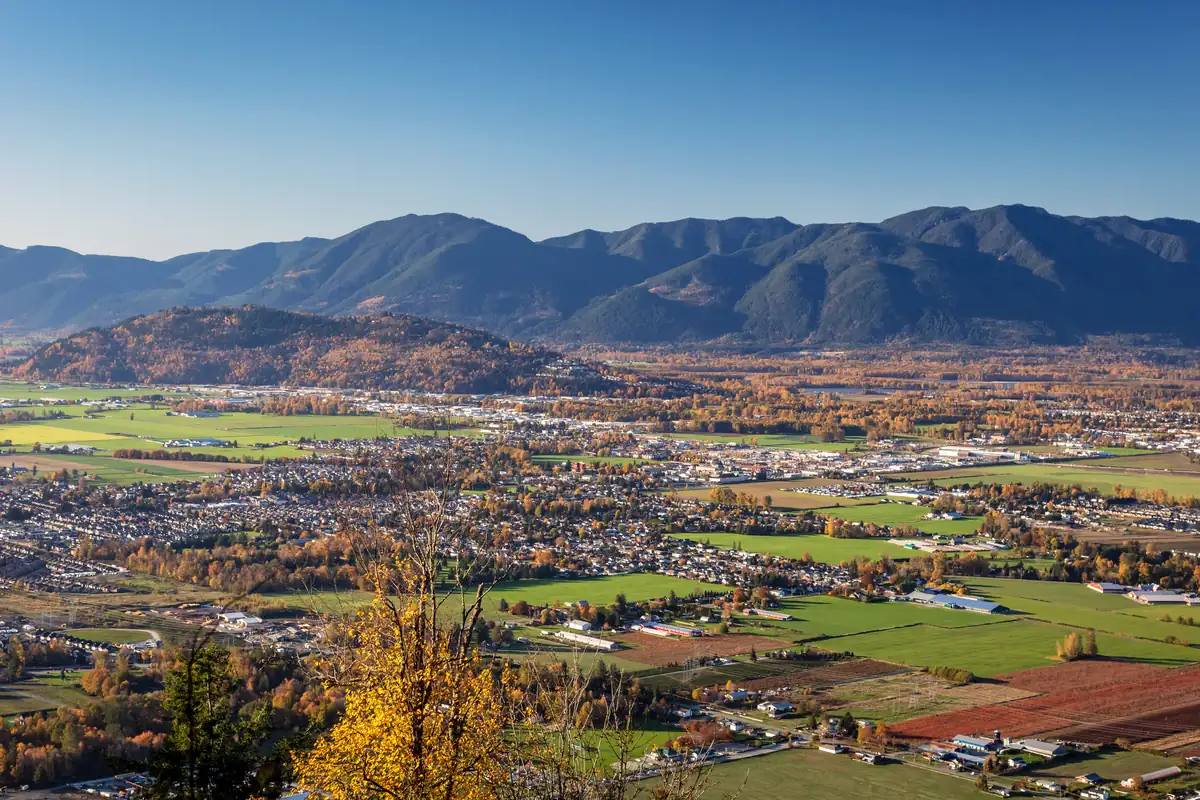Autumn view over Chilliwack, BC, with farmland, neighbourhoods and the surrounding mountains